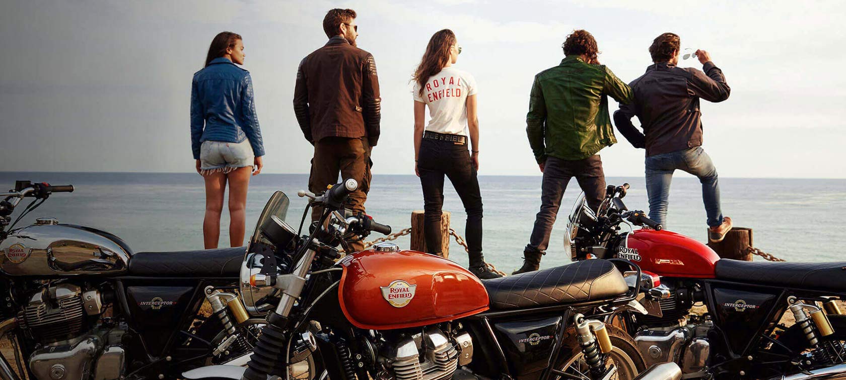 group of rifers with their Royal Enfield bikes near a beach at sunset